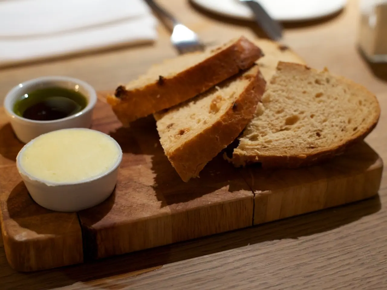 In this image we can see a serving tray which has slices of bread and two bowls of dips.