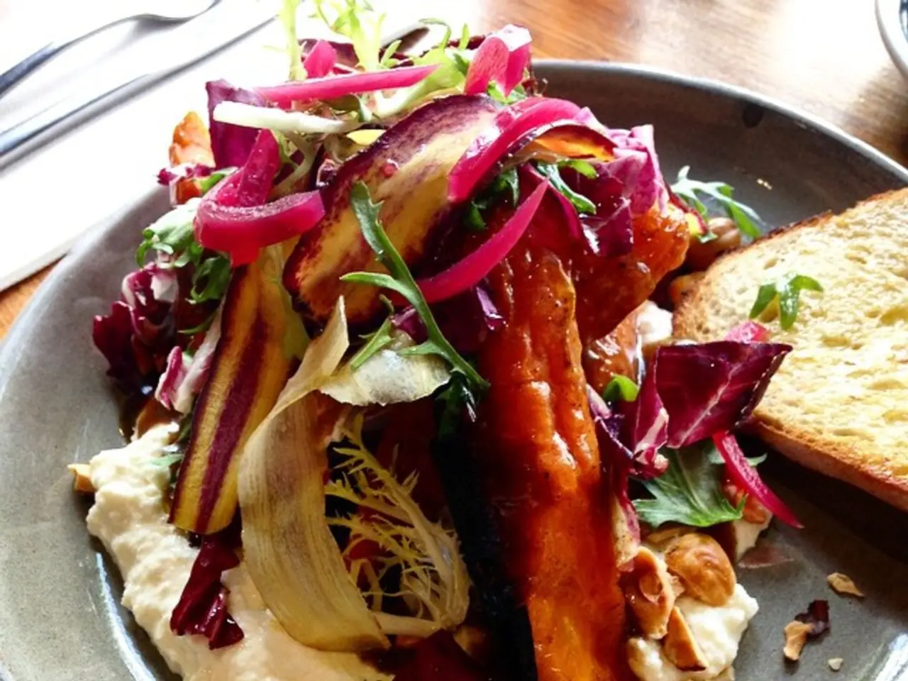 On this wooden surface there is a plate with food and knife.