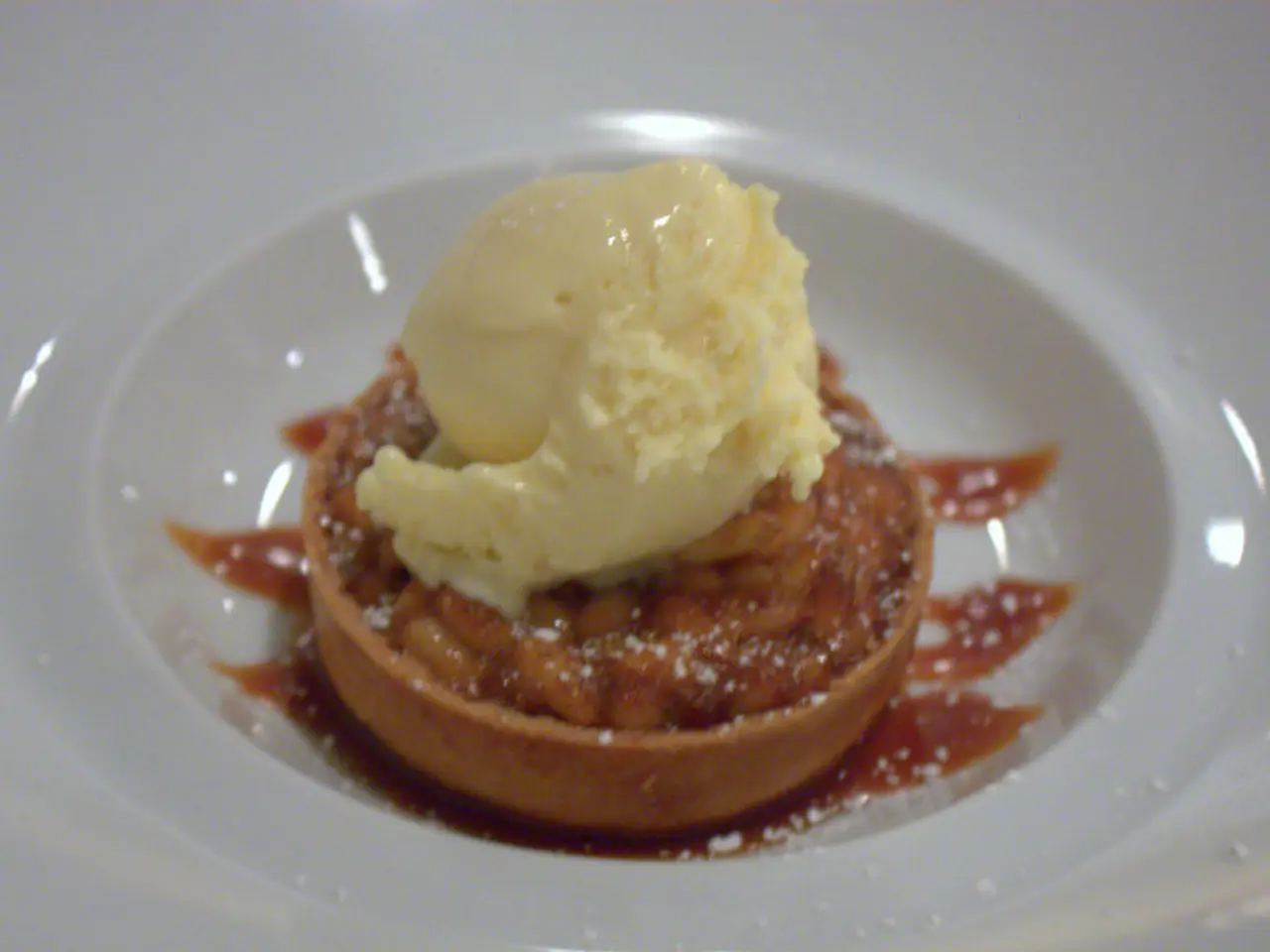 In this picture there is a sweet with mango ice cream places in the white color bowl.