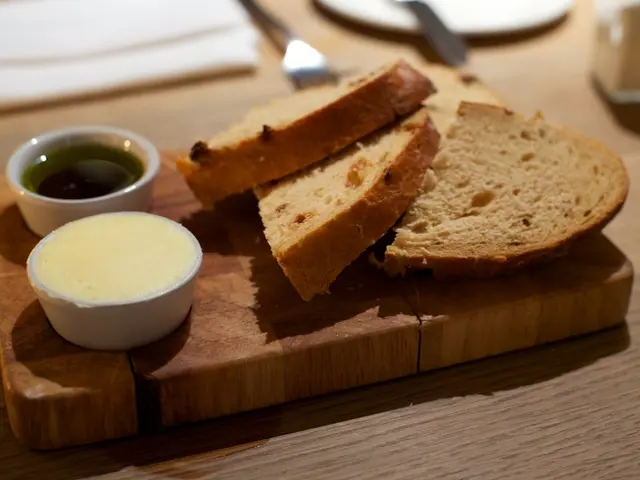In this image we can see a serving tray which has slices of bread and two bowls of dips.