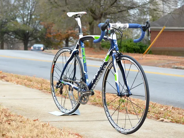 This is a bicycle , on the sidewalk and a house and trees on the side of the road and a car on the...