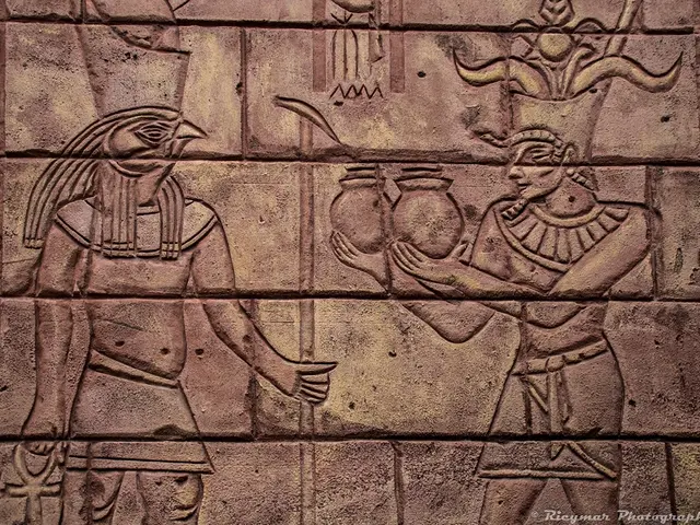 In the picture we can see a wall with some ancient sculptures to it.