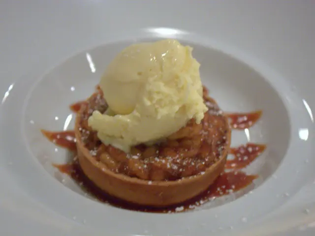 In this picture there is a sweet with mango ice cream places in the white color bowl.